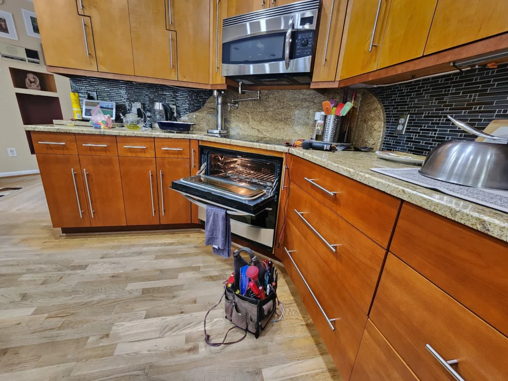 Open electric range with repair tools in a wood-cabinet kitchen